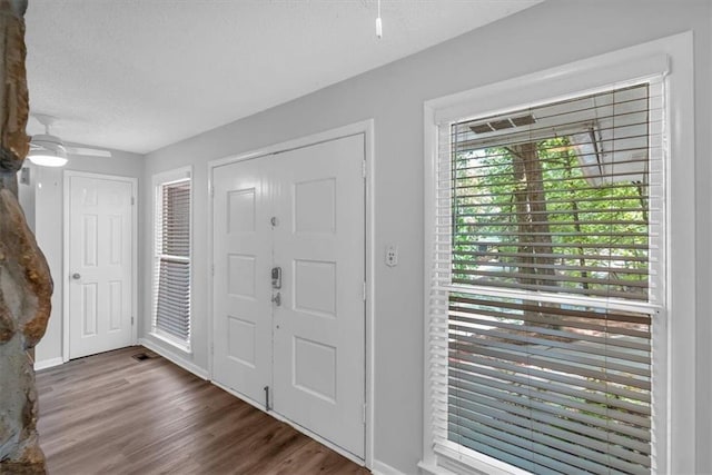 foyer entrance featuring baseboards, a ceiling fan, a textured ceiling, and wood finished floors