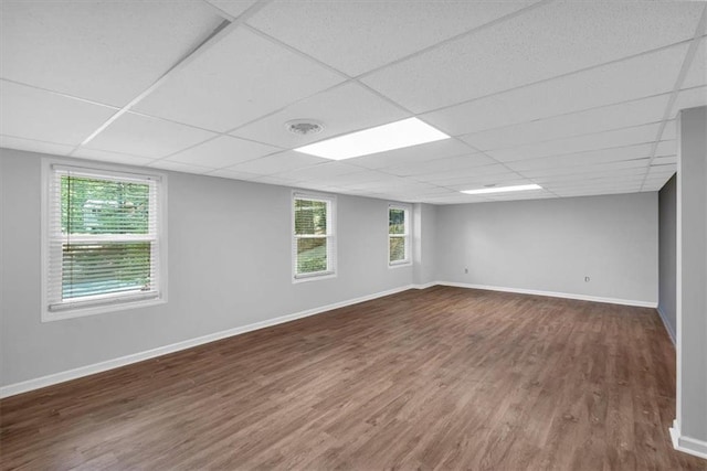 spare room featuring baseboards, a drop ceiling, and wood finished floors