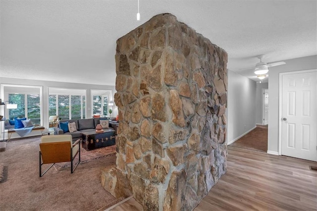 living room featuring a ceiling fan, a textured ceiling, visible vents, wood finished floors, and baseboards