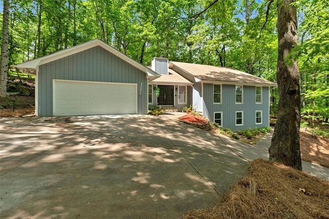 view of front of home with concrete driveway, an attached garage, and a chimney