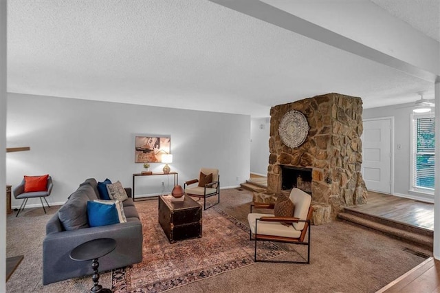 living area featuring ceiling fan, a textured ceiling, a fireplace, wood finished floors, and baseboards