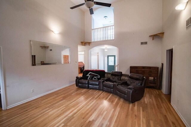 living room with a towering ceiling, wood-type flooring, and ceiling fan