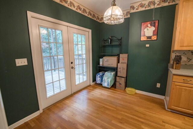 entryway with french doors, a chandelier, and light wood-type flooring