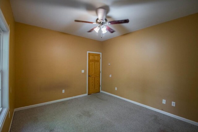 carpeted spare room featuring ceiling fan