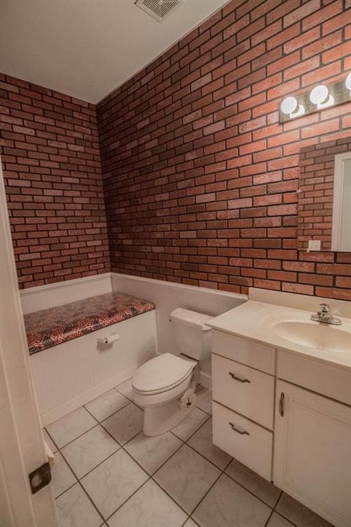 bathroom featuring vanity, tile patterned flooring, toilet, and brick wall