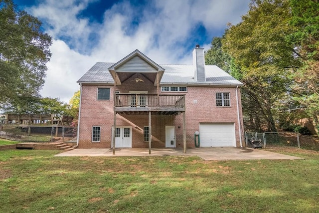 rear view of house with a wooden deck, a patio, a lawn, and a garage