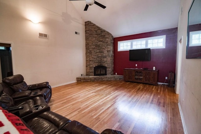 living room featuring high vaulted ceiling, a fireplace, hardwood / wood-style flooring, and a healthy amount of sunlight