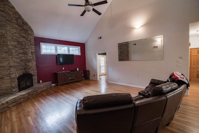 living room featuring hardwood / wood-style flooring, high vaulted ceiling, a fireplace, and ceiling fan