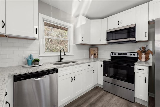 kitchen with white cabinetry, sink, light stone counters, and appliances with stainless steel finishes