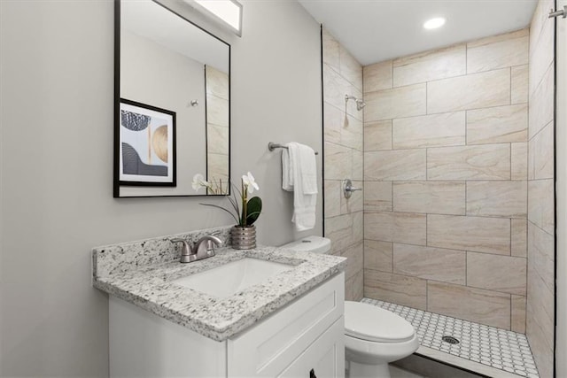 bathroom featuring tiled shower, vanity, and toilet