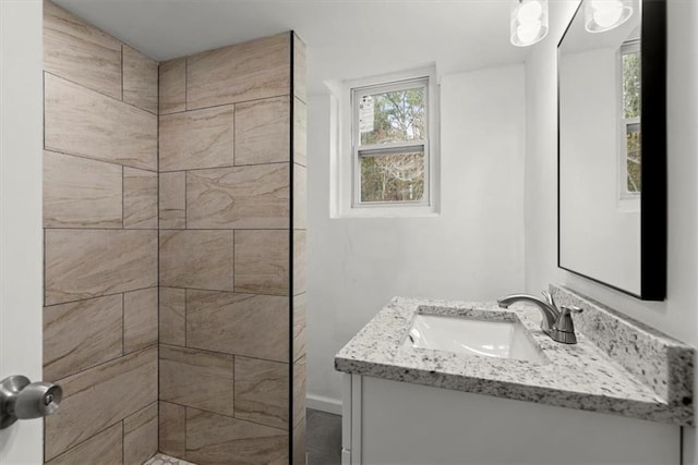 bathroom with a tile shower and vanity