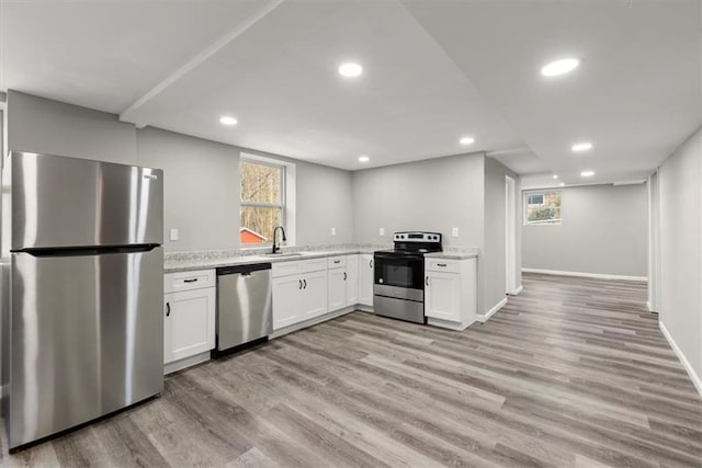 kitchen with white cabinetry, sink, stainless steel appliances, and light stone counters