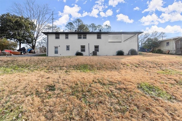 rear view of property featuring central air condition unit and a lawn