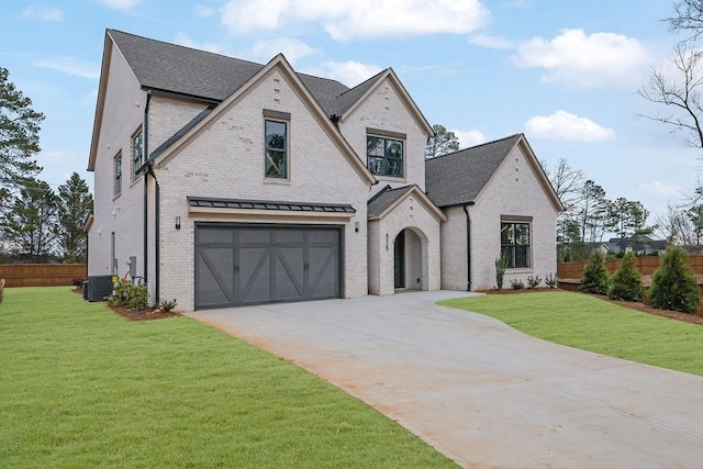 french country style house with central AC, a garage, and a front lawn