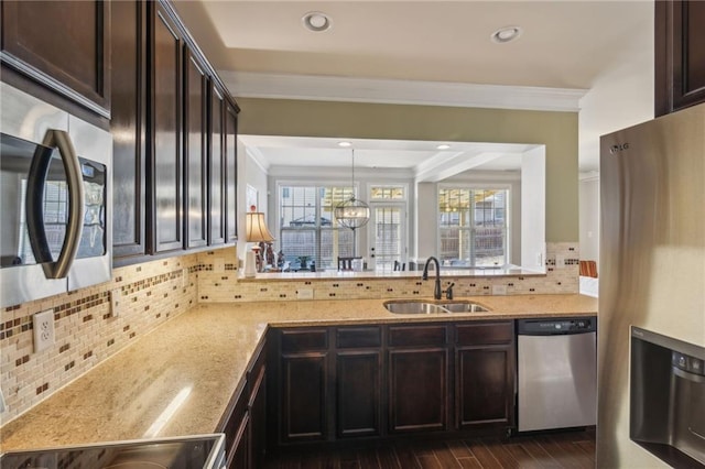 kitchen with pendant lighting, appliances with stainless steel finishes, sink, and dark brown cabinets