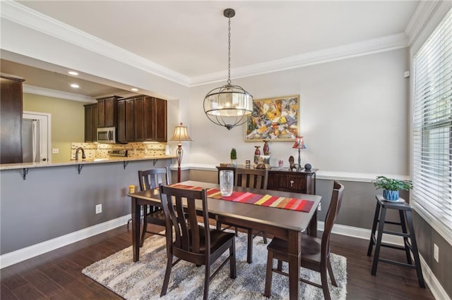 dining area with ornamental molding, dark hardwood / wood-style floors, sink, and an inviting chandelier