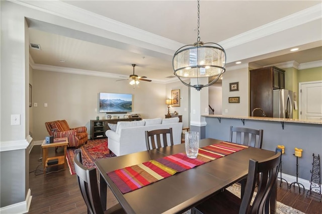 dining area with crown molding, ceiling fan with notable chandelier, and dark hardwood / wood-style flooring