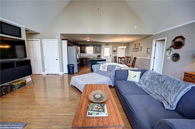 living room featuring high vaulted ceiling, a notable chandelier, baseboards, and wood finished floors