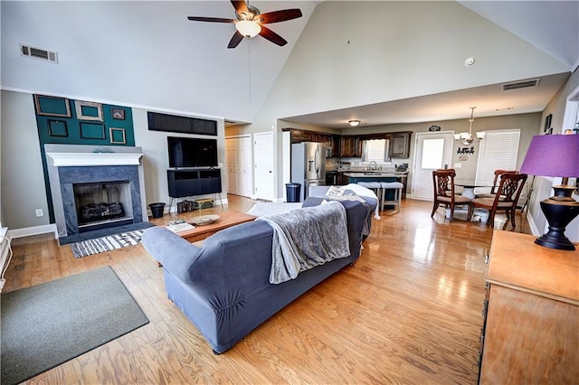 living room featuring ceiling fan with notable chandelier, light wood-type flooring, and visible vents