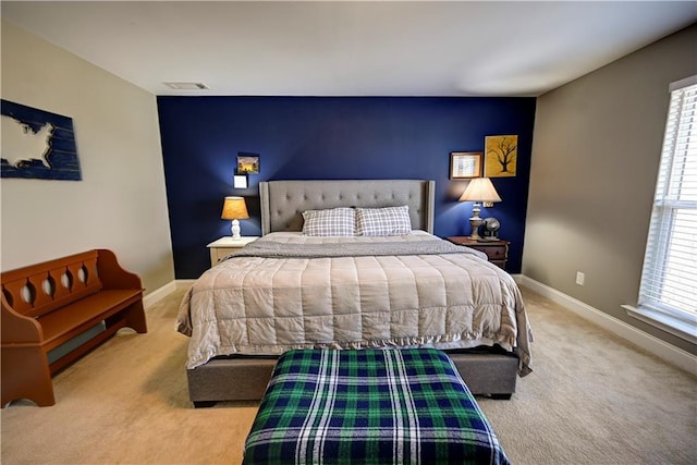 bedroom featuring carpet floors, an accent wall, multiple windows, and baseboards