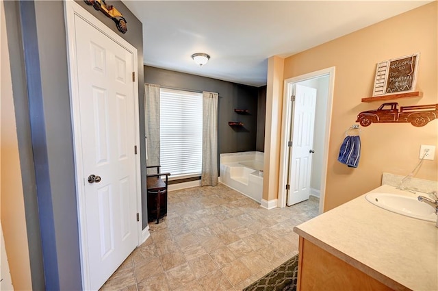 full bathroom featuring baseboards, a bath, and vanity