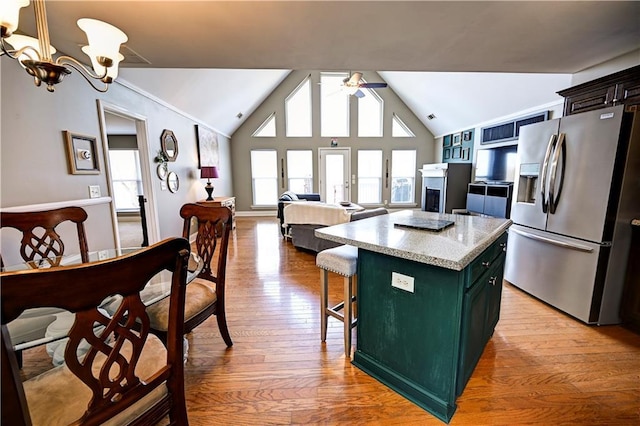 kitchen with stainless steel fridge, light wood-style flooring, a kitchen island, green cabinetry, and ceiling fan with notable chandelier