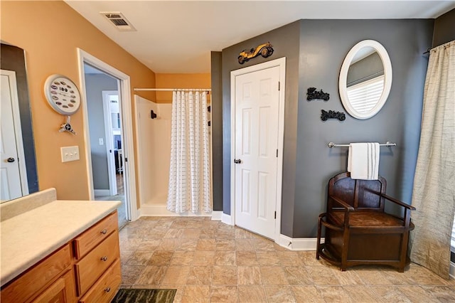 full bath with curtained shower, visible vents, stone finish floor, vanity, and baseboards