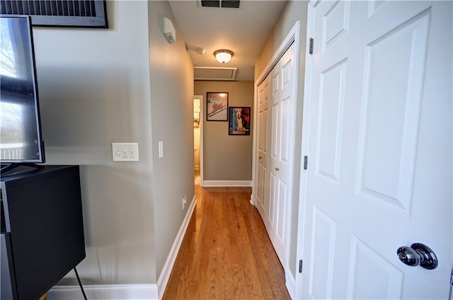 corridor with baseboards, visible vents, and wood finished floors