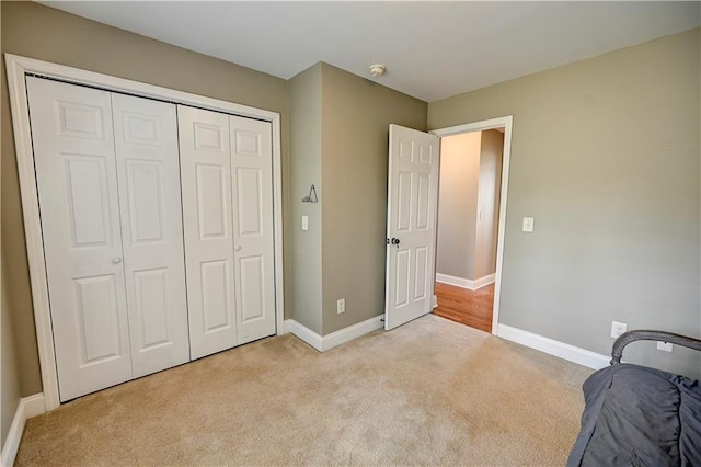 unfurnished bedroom with carpet, a closet, and baseboards