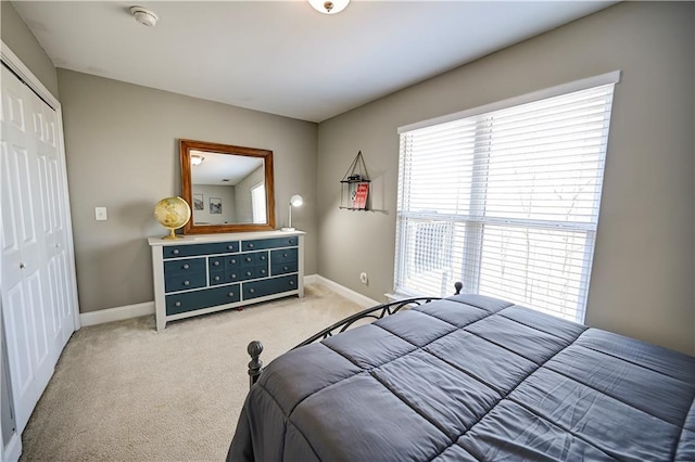 bedroom with a closet, light carpet, and baseboards