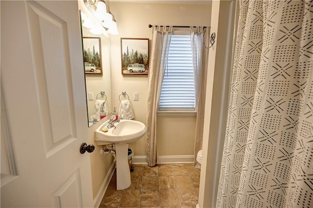 full bath with curtained shower, toilet, and baseboards