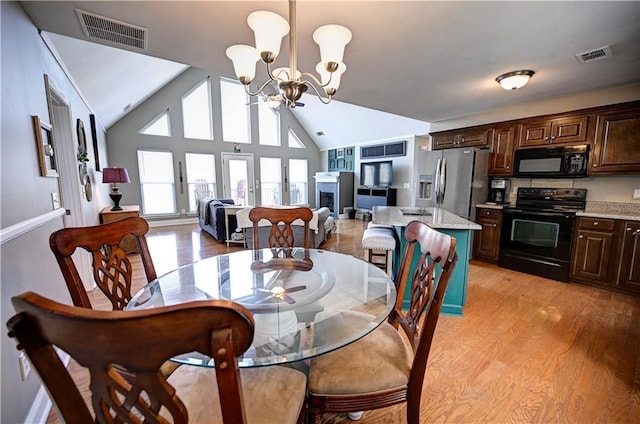 dining room featuring high vaulted ceiling, visible vents, a notable chandelier, and light wood finished floors