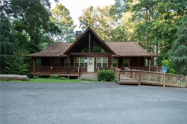 log home featuring covered porch and a chimney