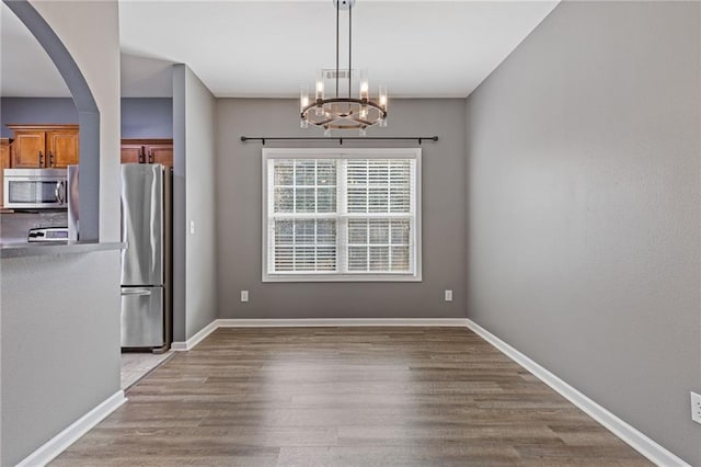 unfurnished dining area featuring hardwood / wood-style flooring and an inviting chandelier