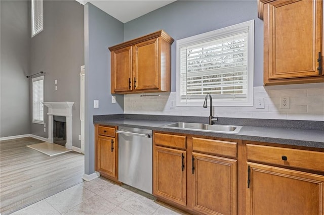 kitchen featuring tasteful backsplash, sink, light tile patterned floors, and stainless steel dishwasher