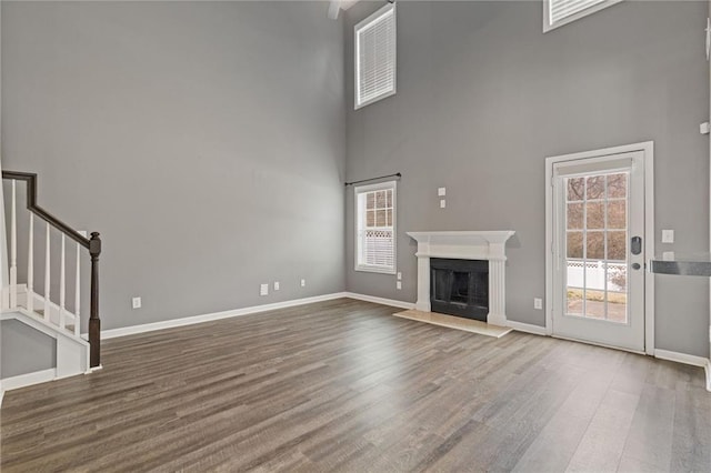 unfurnished living room featuring hardwood / wood-style flooring and a towering ceiling