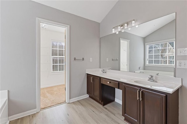 bathroom with vanity, vaulted ceiling, hardwood / wood-style floors, and a tub