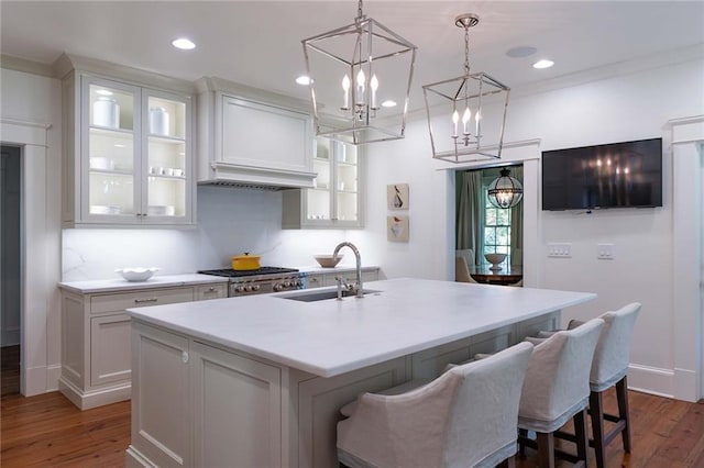 kitchen featuring white cabinets, dark hardwood / wood-style flooring, a center island with sink, and sink