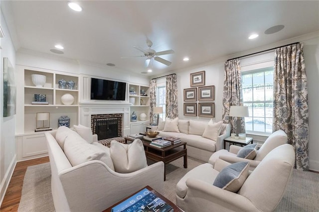 living room featuring a brick fireplace, ceiling fan, ornamental molding, and hardwood / wood-style flooring