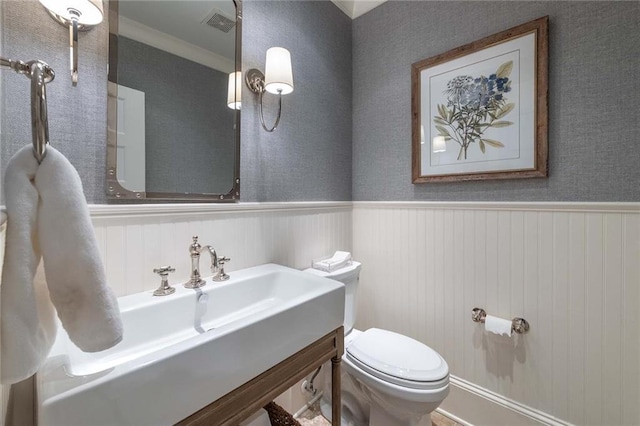 bathroom with toilet, ornamental molding, and sink