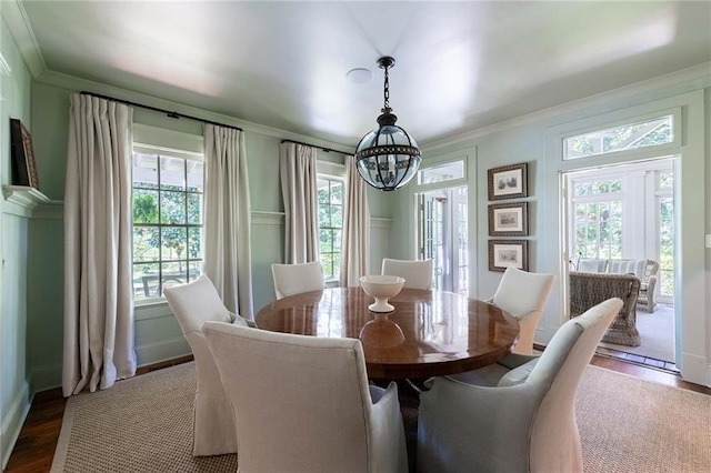 dining space featuring crown molding, dark wood-type flooring, and a chandelier