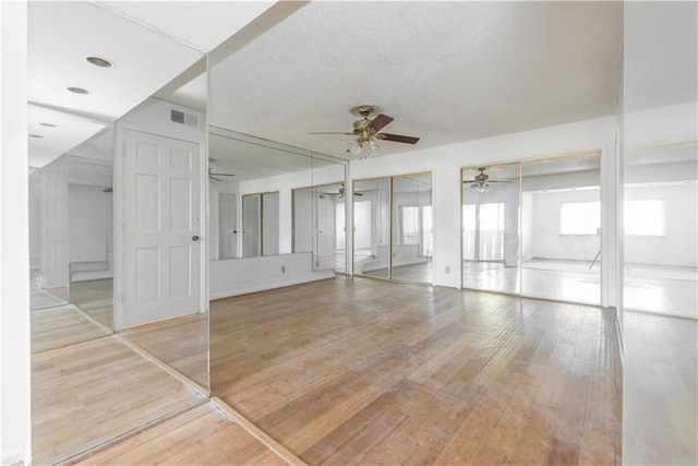 empty room with visible vents, ceiling fan, a textured ceiling, and light wood finished floors