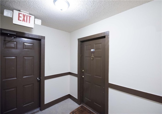 entryway with a textured ceiling, tile patterned floors, and baseboards