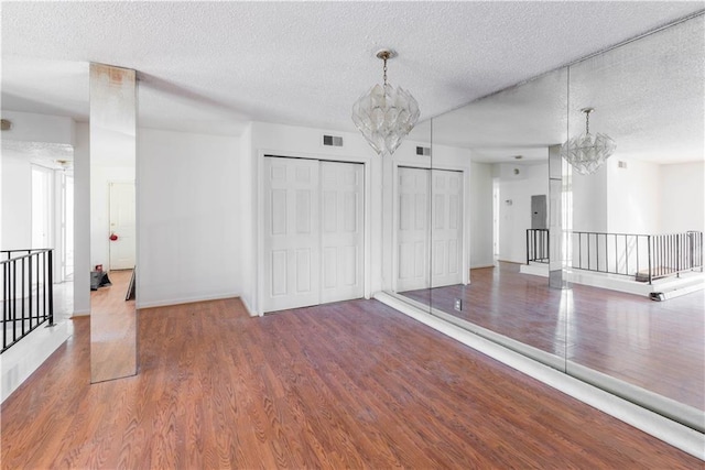 unfurnished room with visible vents, a chandelier, and wood finished floors