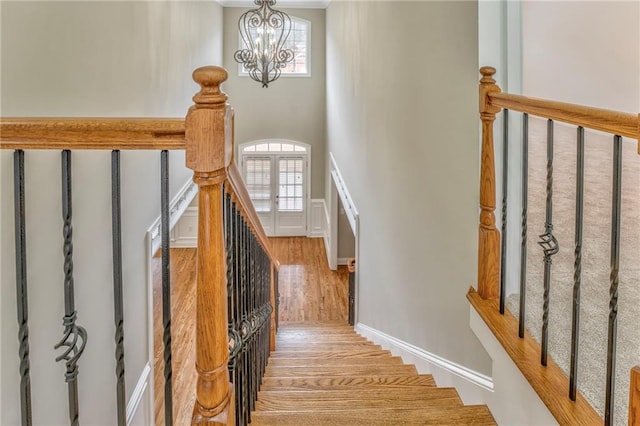 stairs featuring a towering ceiling and a chandelier