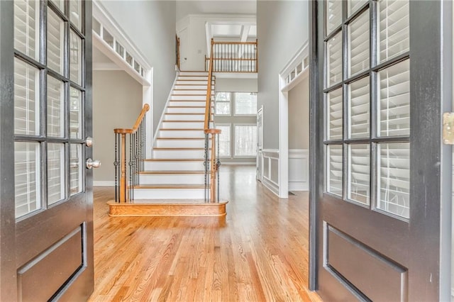 entryway with hardwood / wood-style flooring, ornamental molding, and a high ceiling