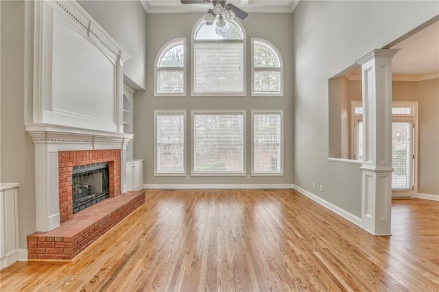 unfurnished living room featuring a brick fireplace, crown molding, and ornate columns