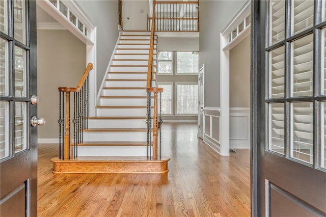 foyer with hardwood / wood-style floors, ornamental molding, and a high ceiling