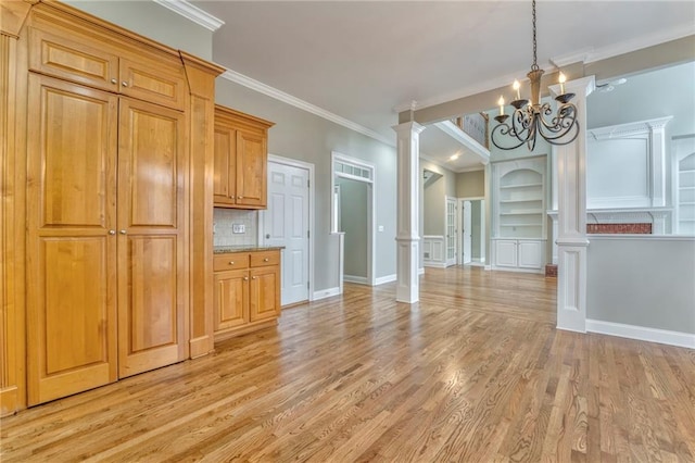 interior space featuring tasteful backsplash, built in features, ornamental molding, and decorative columns