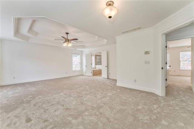 unfurnished living room with plenty of natural light, light carpet, and a tray ceiling